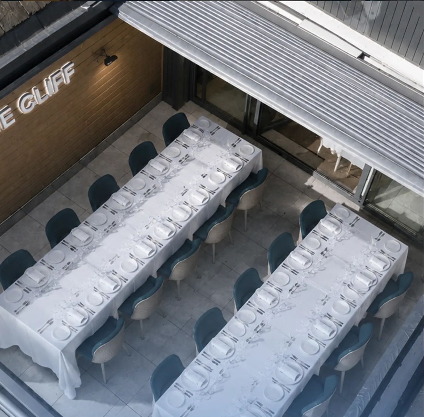 Two long tables laid for dinner on the rooftop, seen from above
